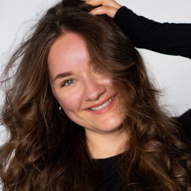 Fiona von Fiografie, lächelnd mit langen, gewellten Haaren